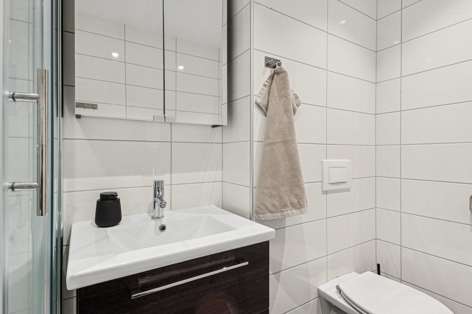 Baderomsinnredningen består av en praktisk servantseksjon med nedfelt vask og veggmontert toalett. Galleribilde