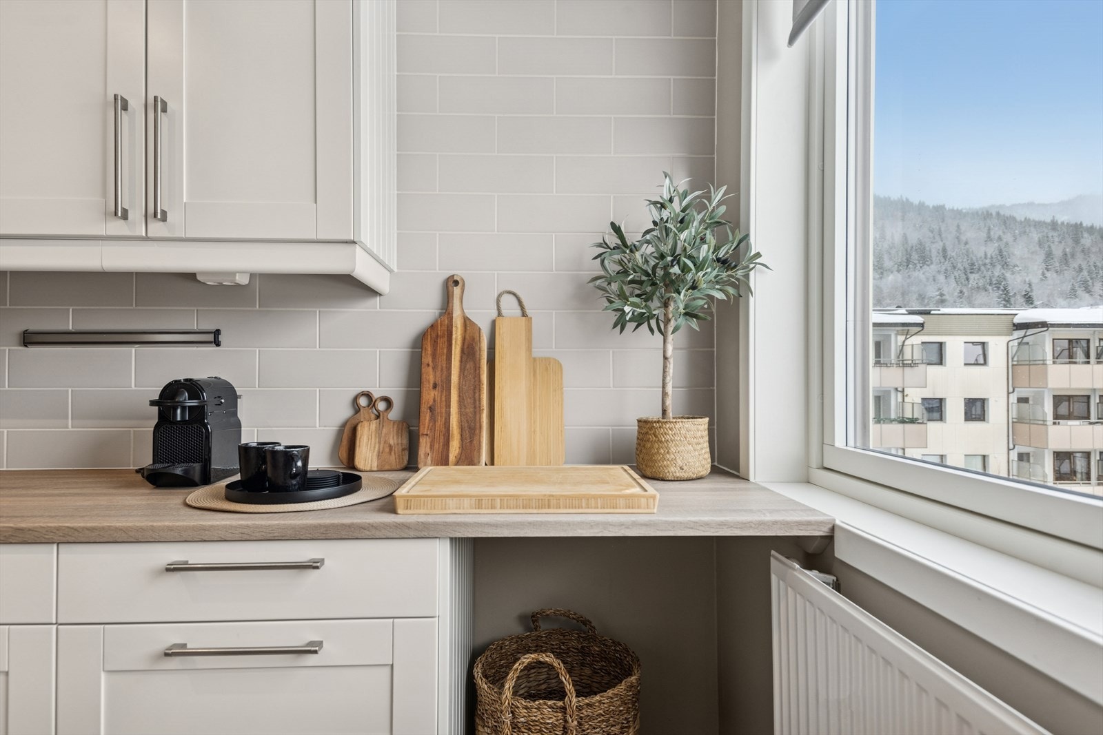 Lyst og innbydende kjøkken fylt med koselige detaljer med nytraktet kaffe, favorittkopper og brødfjøler som skaper en lun og hjemmekoselig stemning. Galleribilde