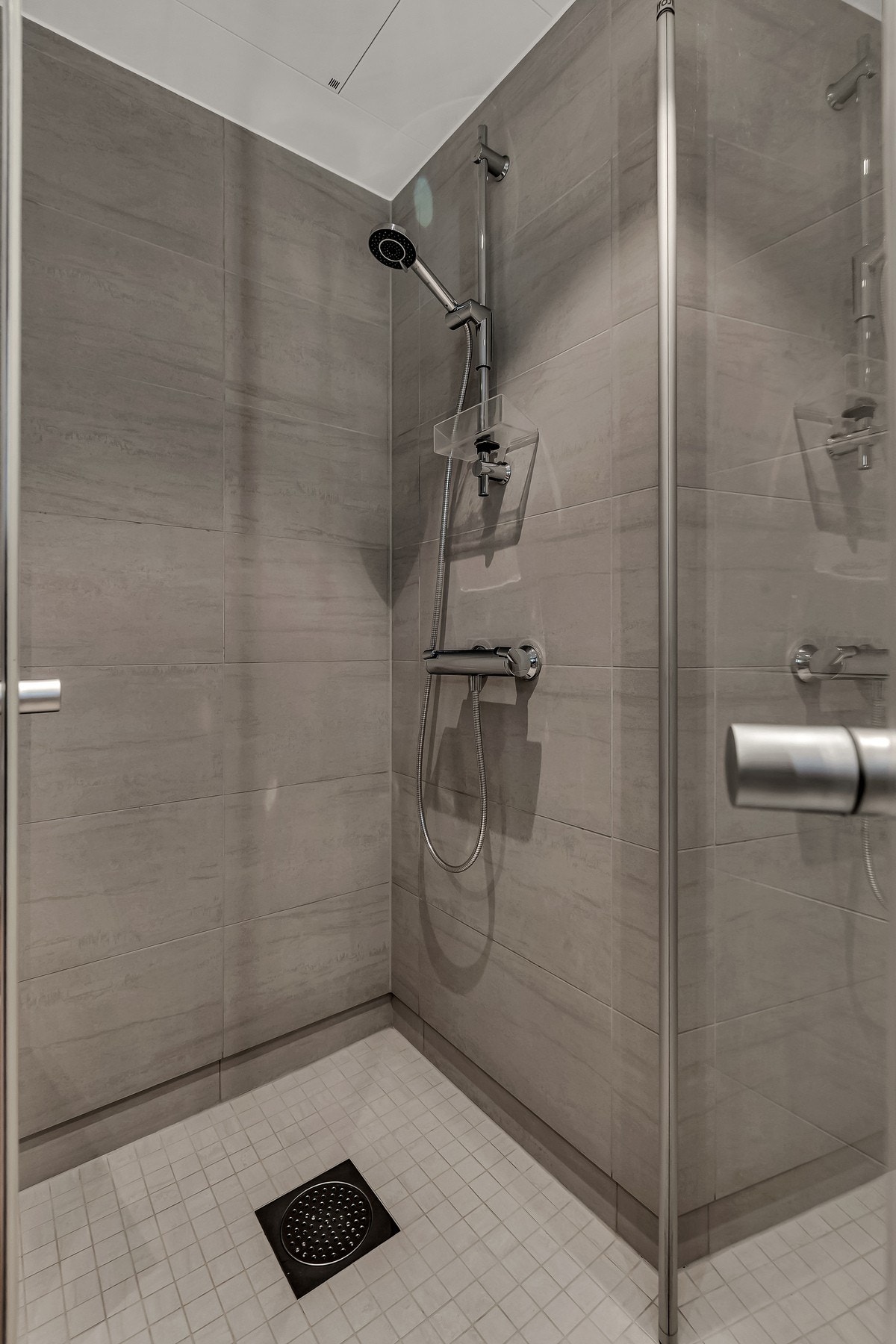 Badet er delikat med mørkere fliser på gulv og vegger, med downlights i himlingen. Galleribilde