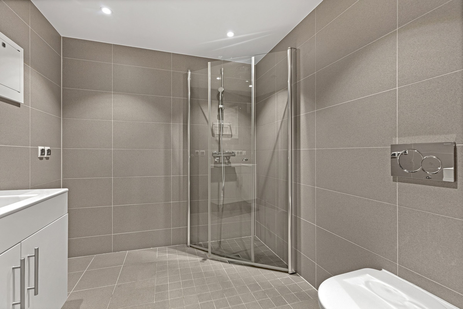 Badet er utstyrt med dusjhjørne med innfellbare glassdører og opplegg for vaskemaskin. Galleribilde