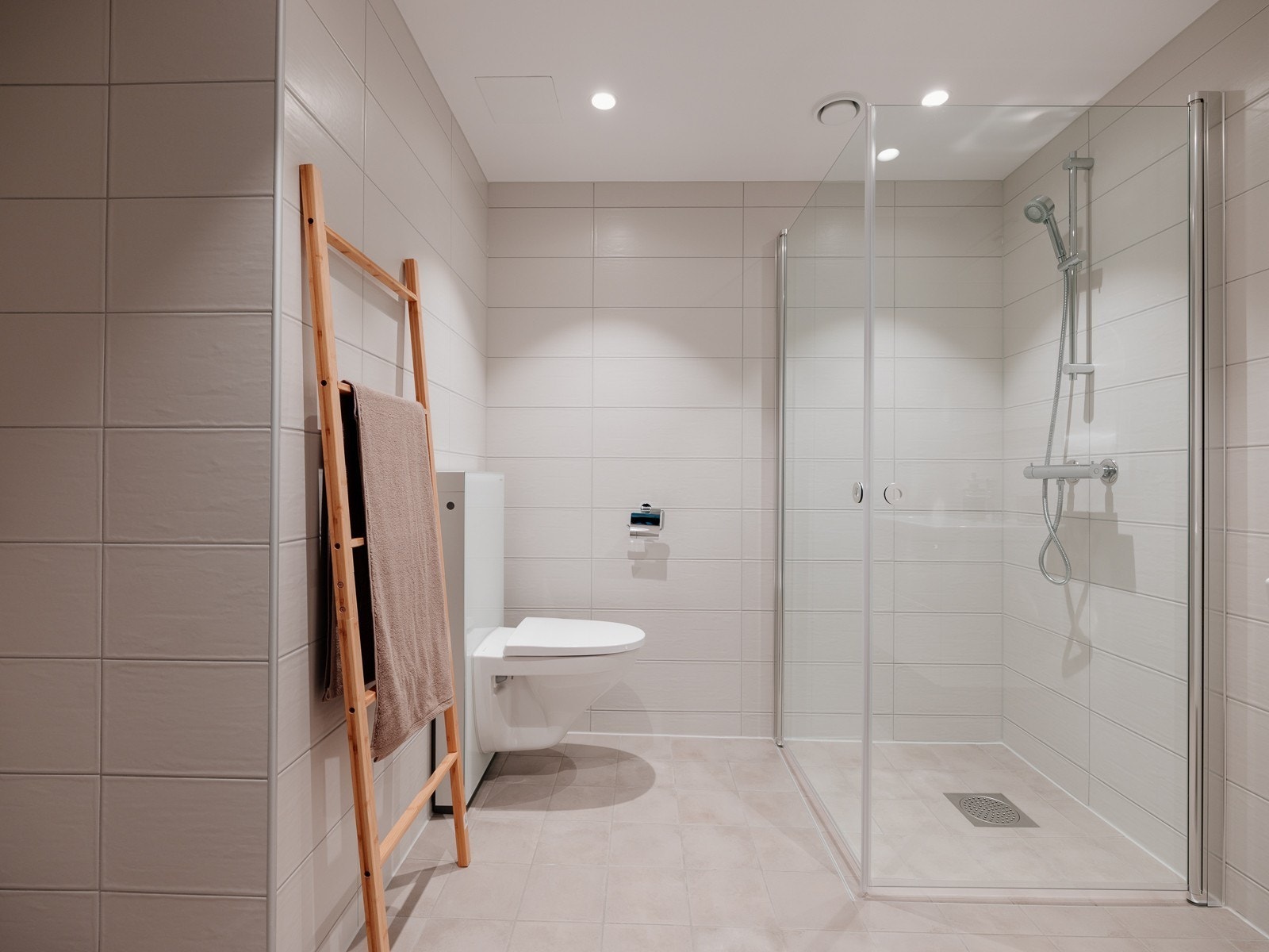 Lekkert flislagt bad med Geberit Monolith sisterne samt dusj med innfellbare glassdører Galleribilde