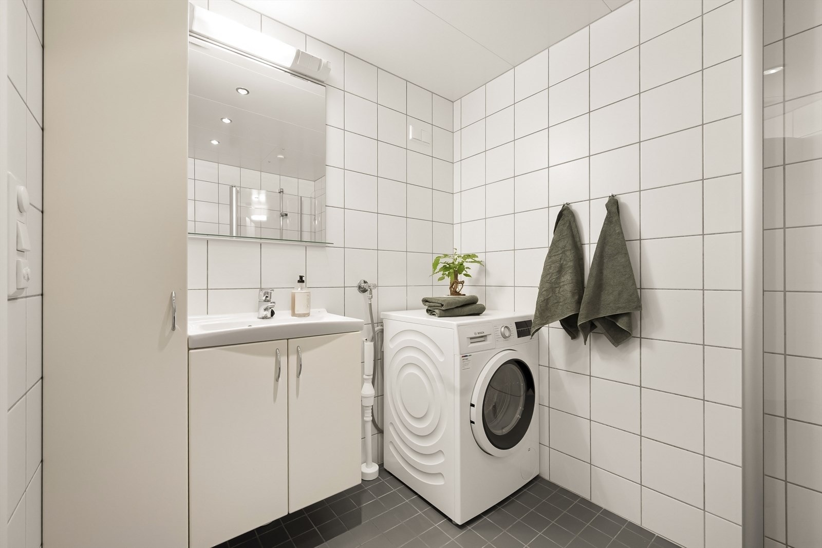 Badet er utstyrt med vegghengt toalett, servantinnredning og opplegg for vaskemaskin. Galleribilde