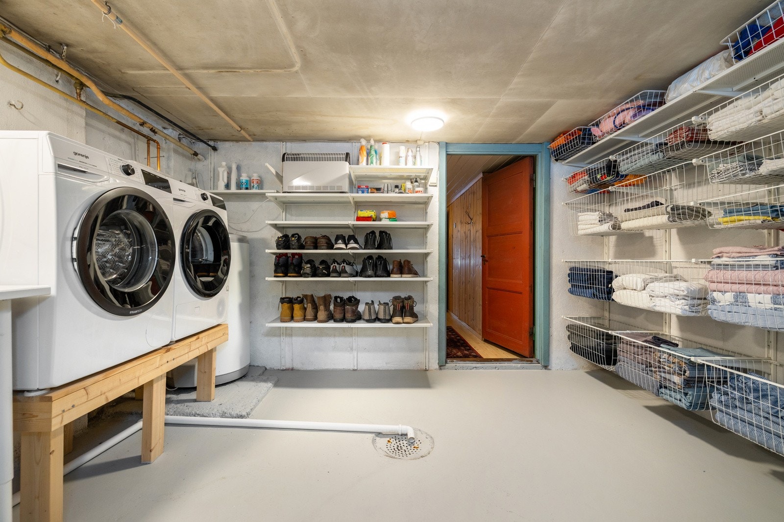 Rommet er innredet med vaskemaskin og tørketrommel, benkeplate med arbeidsflate, utslagsvask samt åpne hyller og oppbevaringsløsninger som gir god organisering. Galleribilde