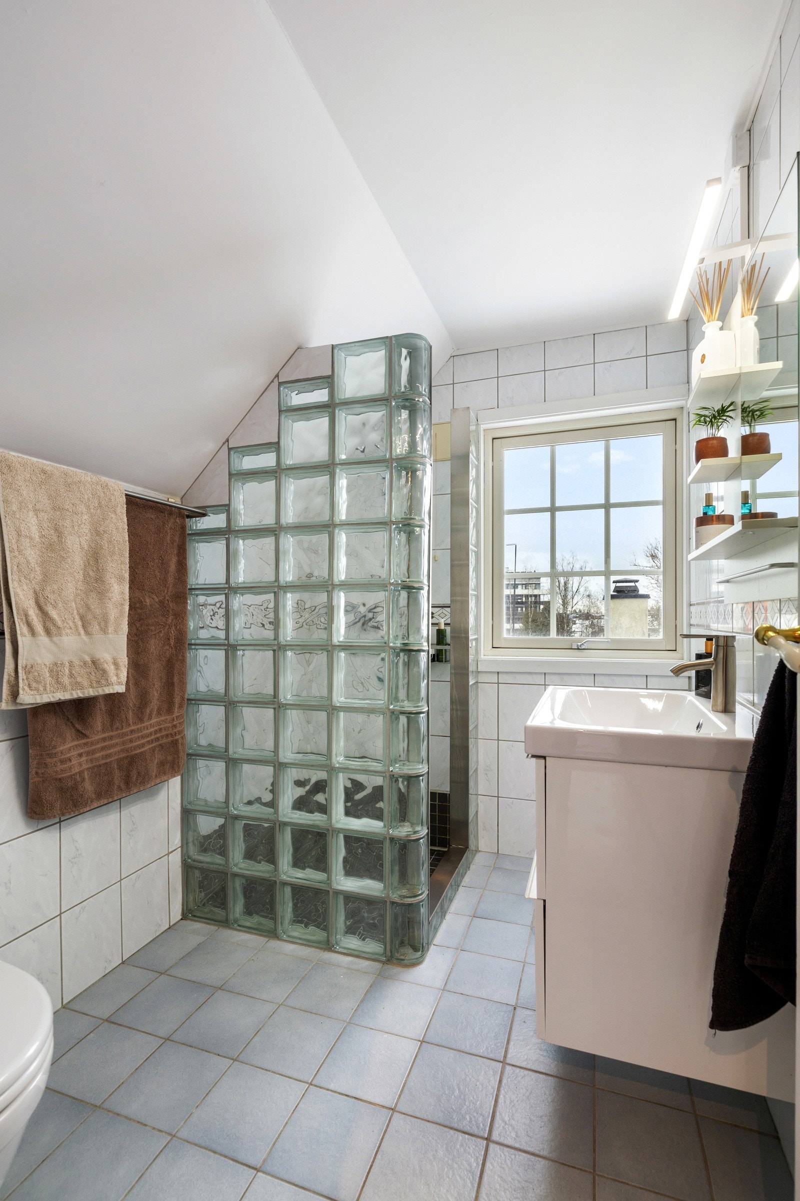 Badet i andre etasje har fliser på vegger og gulv i lyse, nøytrale farger som gir et rent og ryddig uttrykk. Galleribilde