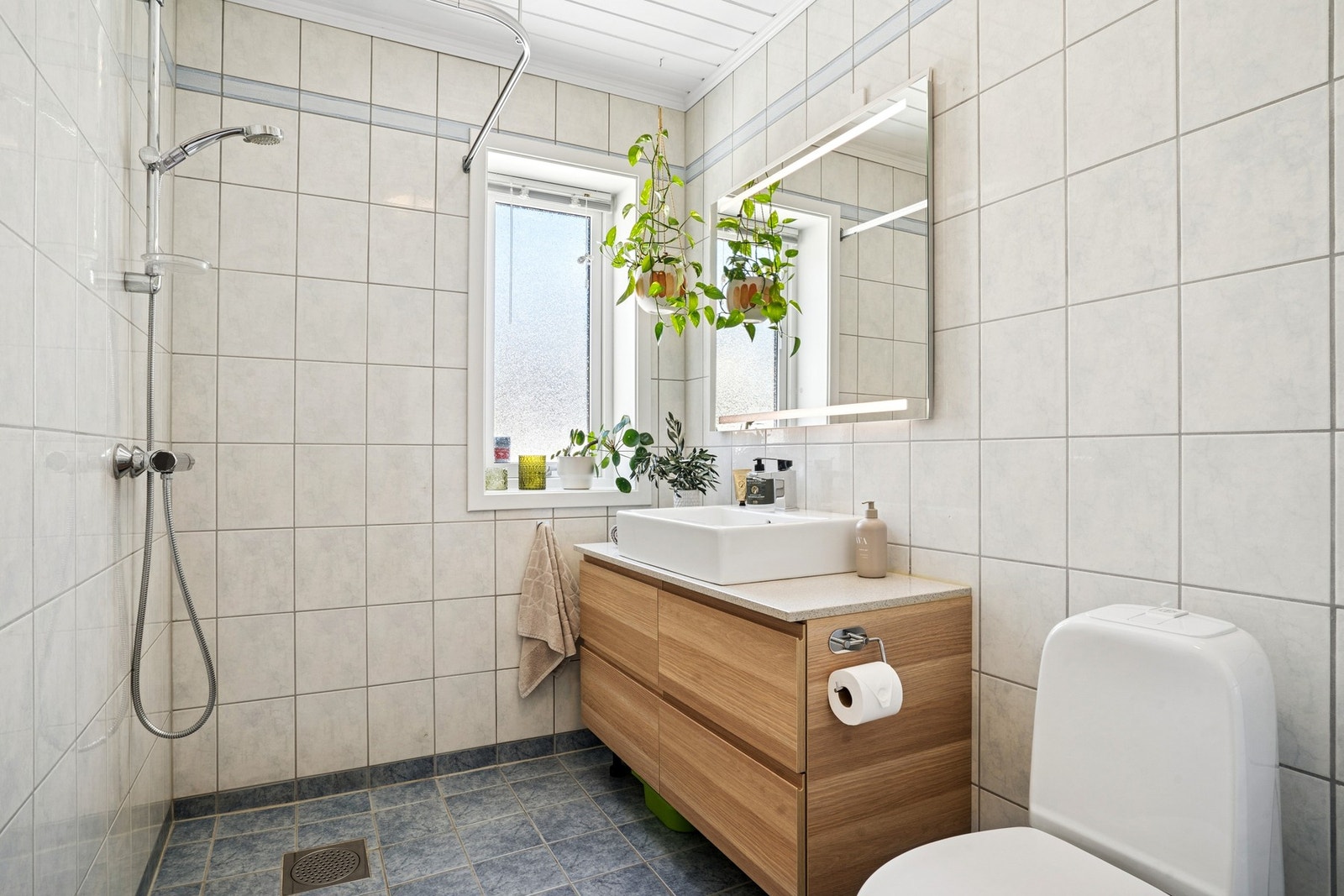 Praktisk flislagt bad i husets 1. etasje. Badet har dusj, toalett og baderomsinnredning. Galleribilde