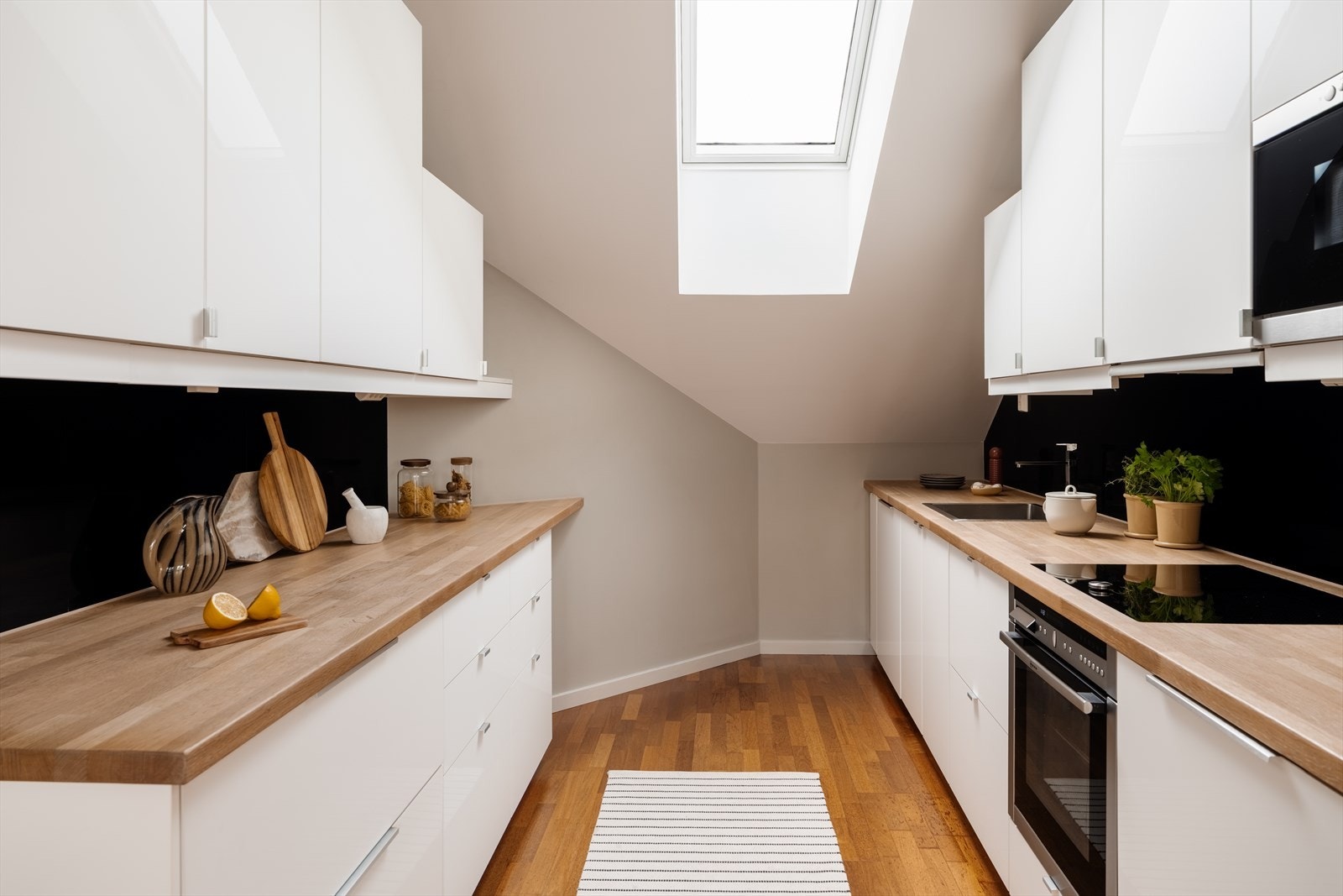 Lyst, moderne kjøkken med glatte fronter og benkeplater i eik. Galleribilde