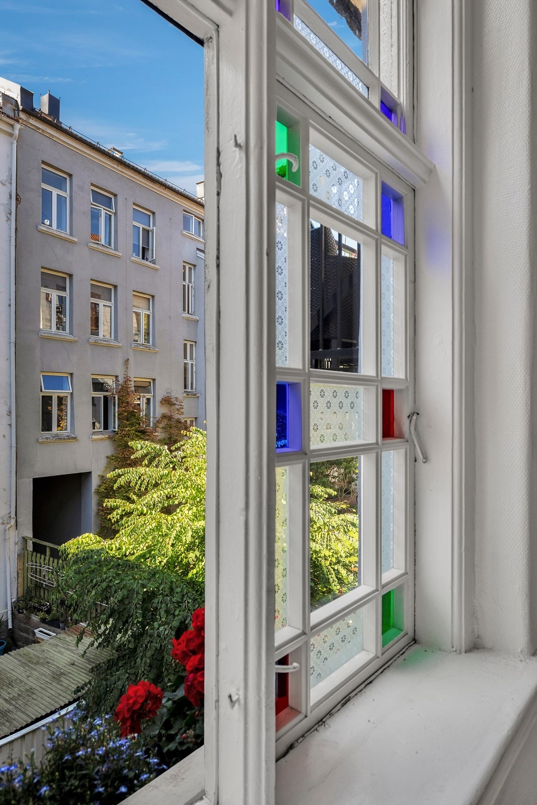 Sommerbilde tatt fra vinduet i trappeoppgangen med utsyn til grønne og frodige omgivelser. Galleribilde