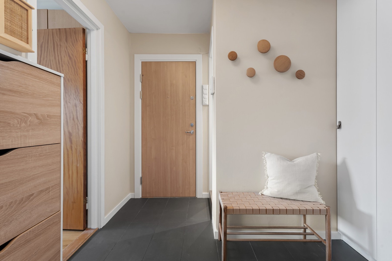 Lys og romslig entré med nyere dørcalling-anlegg. Rommet har fliser på gulv med gulvvarme, mens et praktisk garderobeskap gir god plass for yttertøy og sko. Galleribilde