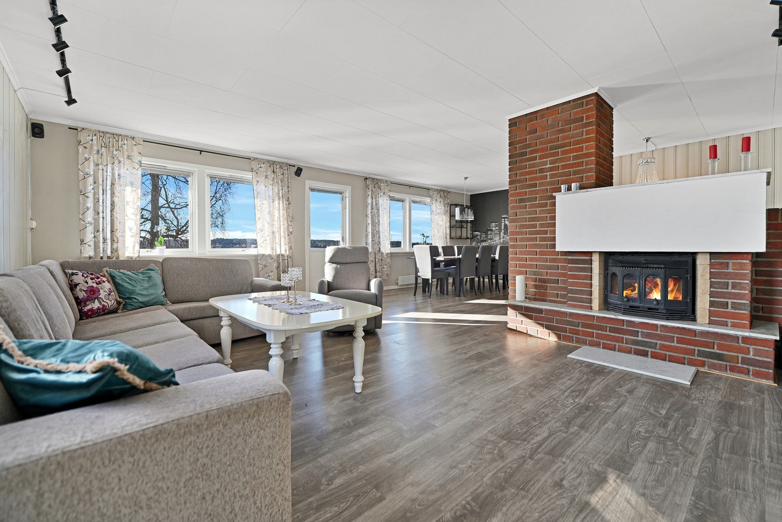 Store vinduer gir godt med naturlig lys i stuen, som har en koselig peis og åpen løsning mot spisestuen. Galleribilde