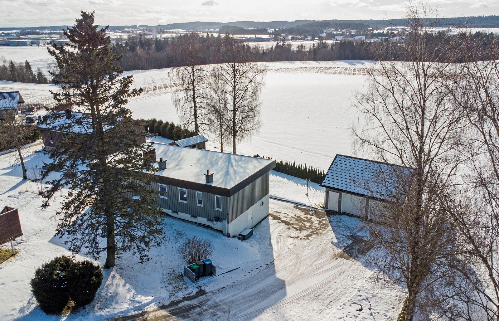 Boligen ligger i et rolig område med utsikt over snødekte marker og skogkledde åser i bakgrunnen. Galleribilde