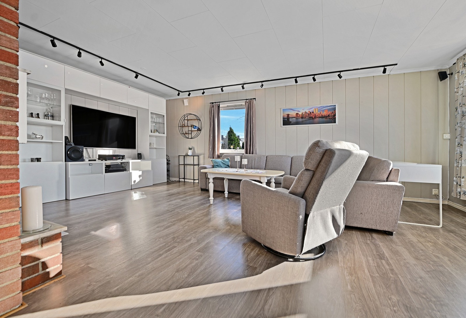 Lyst rom med stort vindu, moderne veggseksjon og parkettgulv. Galleribilde