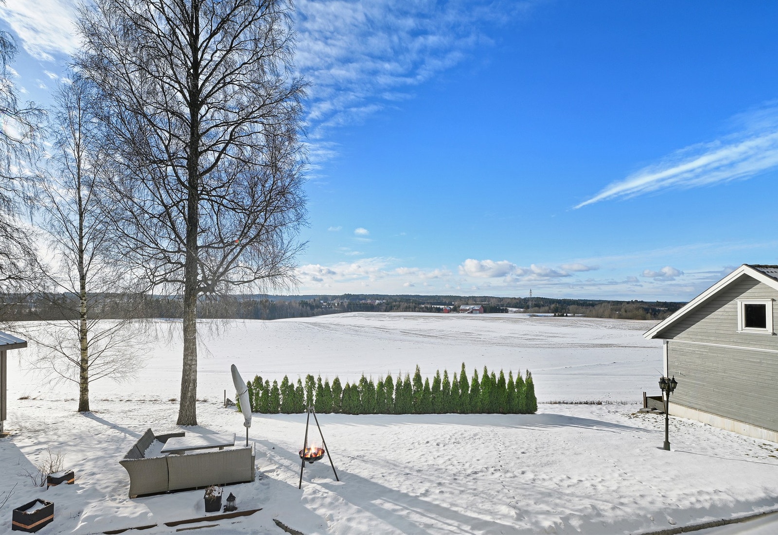 Utsikt mot snødekte marker og åpent landskap med klar blå himmel. Galleribilde
