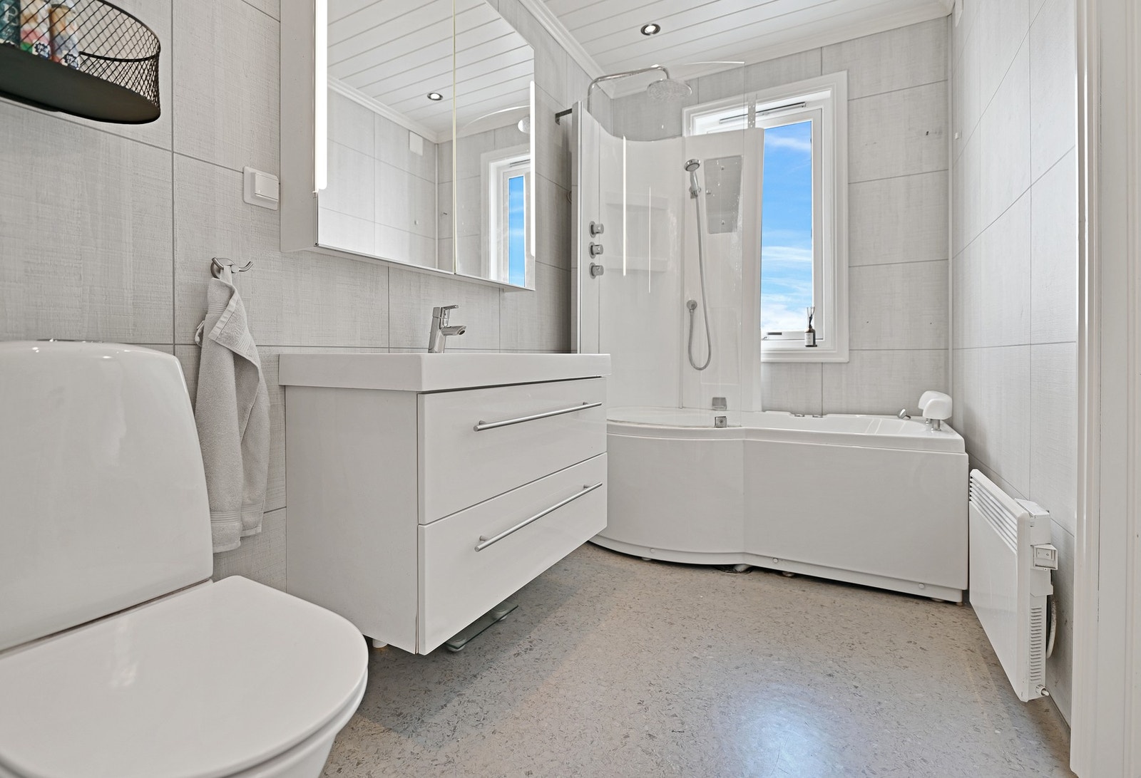 Lyst bad med dusjkabinett, servant med speil, og vindu som gir naturlig lys. Galleribilde