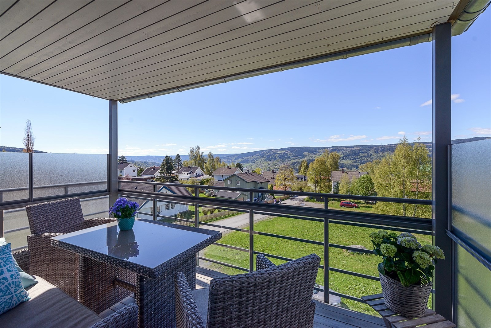 Balkongen har impregnert tregulv og god plass til sittegruppe. (Bildet er tatt på sommeren. I forbindelse med utbygging av ledningsnettet benytter kommunen midlertidig friarealet på nedsiden til lagring av materialer og utstyr.) Galleribilde