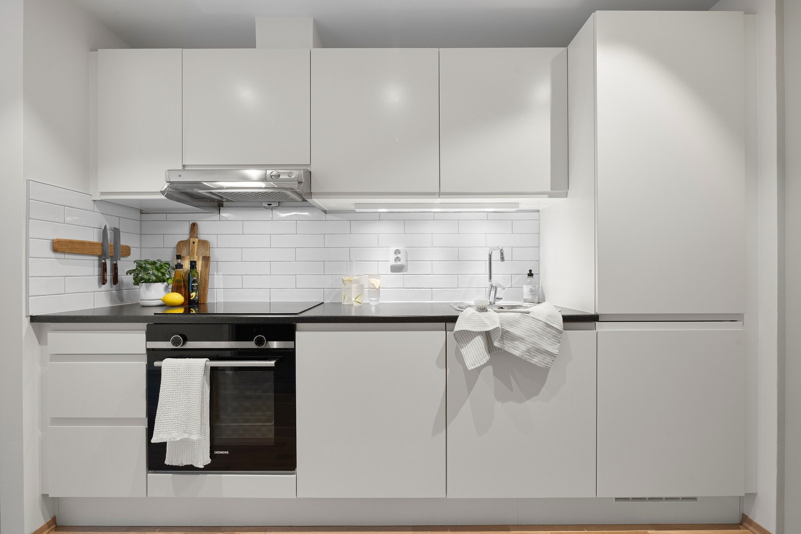 Den mørke benkeplaten står i fin kontrast til det lyse kjøkkenet. Under overskapene er det etablert spotter for god belysning, samt innfelte downlights i himling. Galleribilde