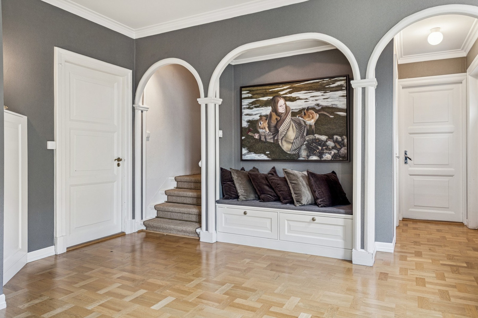 Stilfull mellomgang med dekorative buer og integrert benk med oppbevaring - et innbydende bindeledd mellom etasjene. Galleribilde