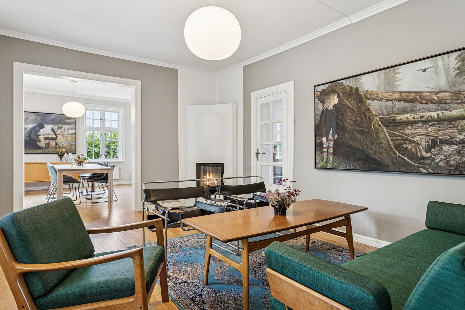 Stuen har en lun og hyggelig atmosfære med peis som naturlig samlingspunkt. Den brede åpningen mot spisestuen gir en luftig romfølelse og gode sosiale soner. Galleribilde