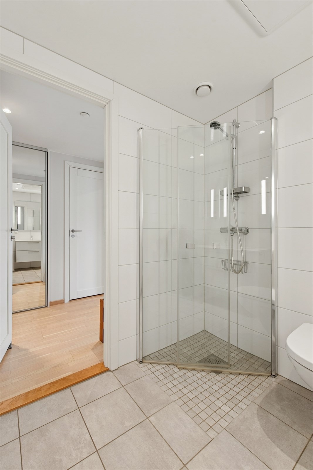 Badet er innredet med servant med ettgreps blandebatteri, vegghengt toalett og dusjhjørne med glassdører. Galleribilde