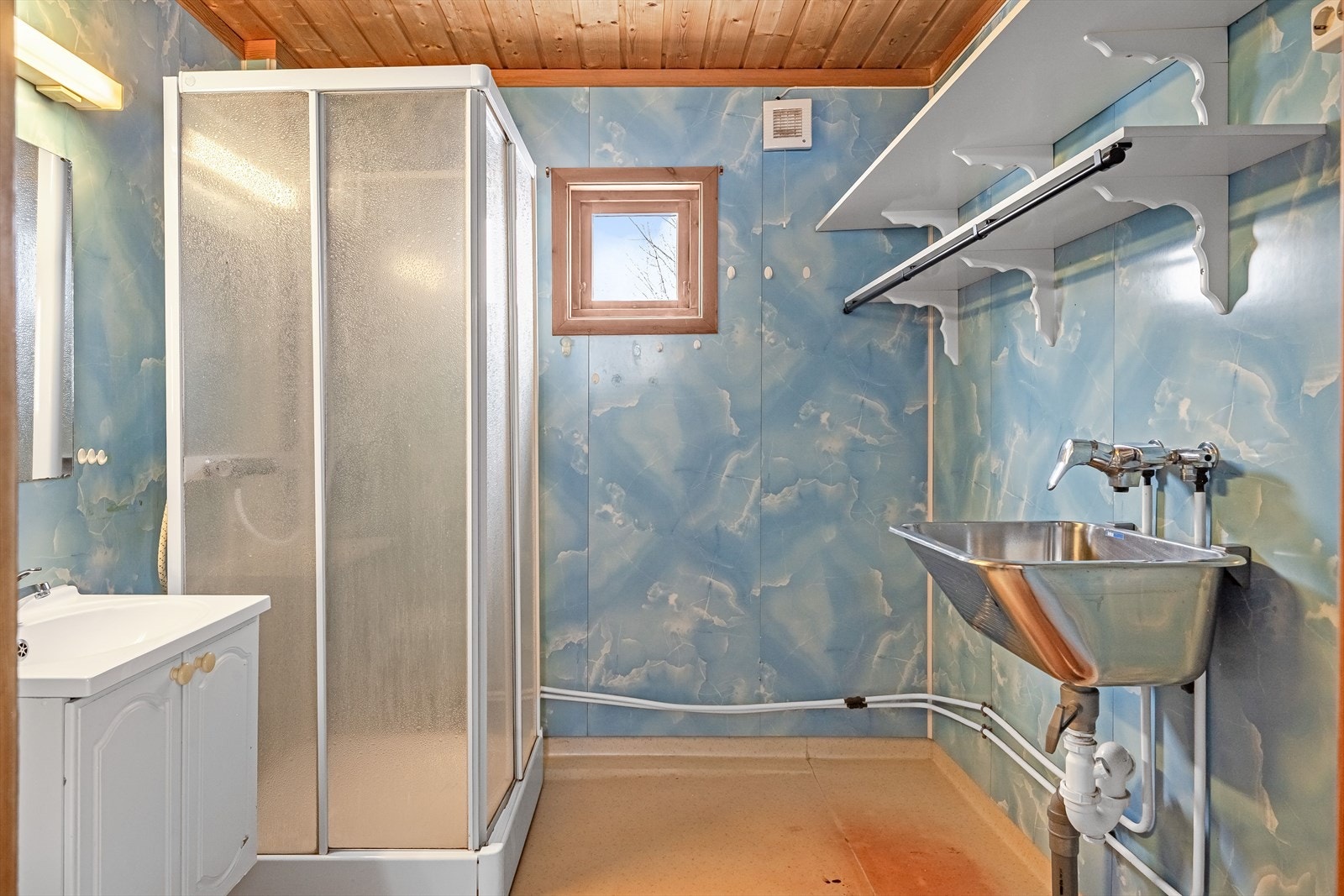 Bad/vaskerom fra 1980-tallet med våtromsbelegg på gulv, elektriske varmekabler, våtromsplater på veggene og elektrisk vifte. Galleribilde