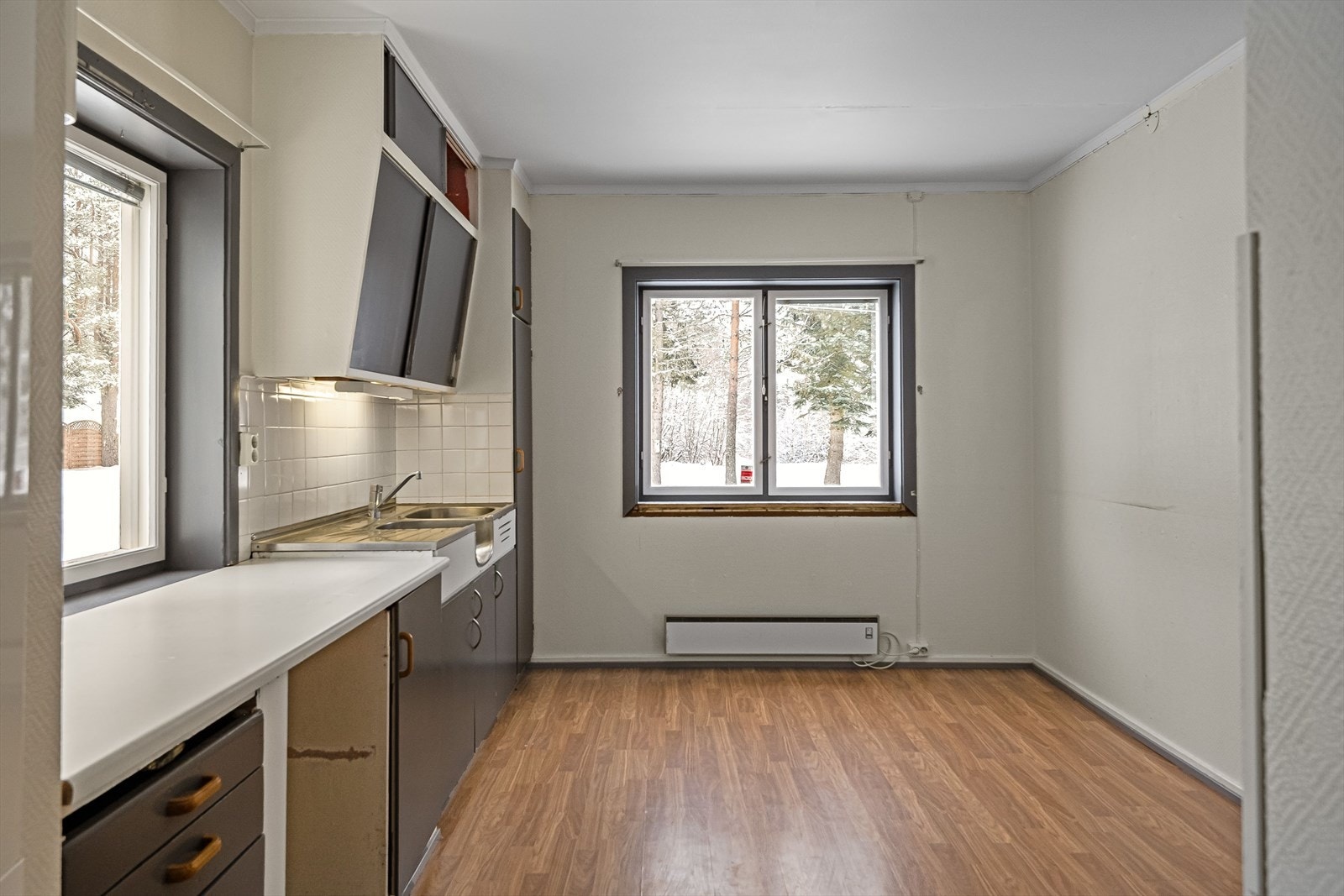 Kjøkkeninnredningen har glatte fronter, laminert benkeplate og benkebeslag med nedfelt dobbel oppvaskkum. Lyse fliser i benkeryggen og belysning under overskap. Galleribilde