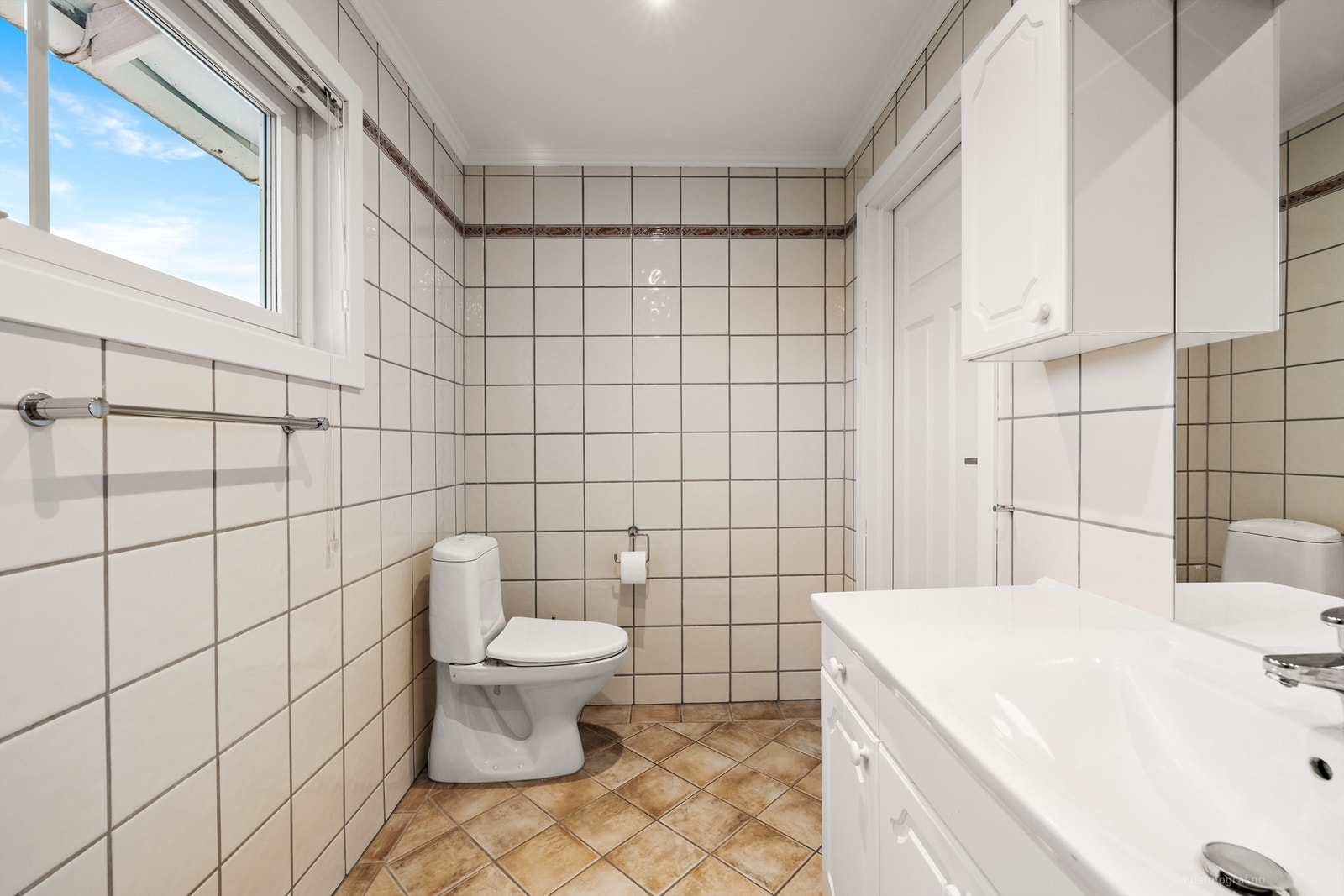 Badet er innredet med servantmøbel, toalett og badekar. Galleribilde