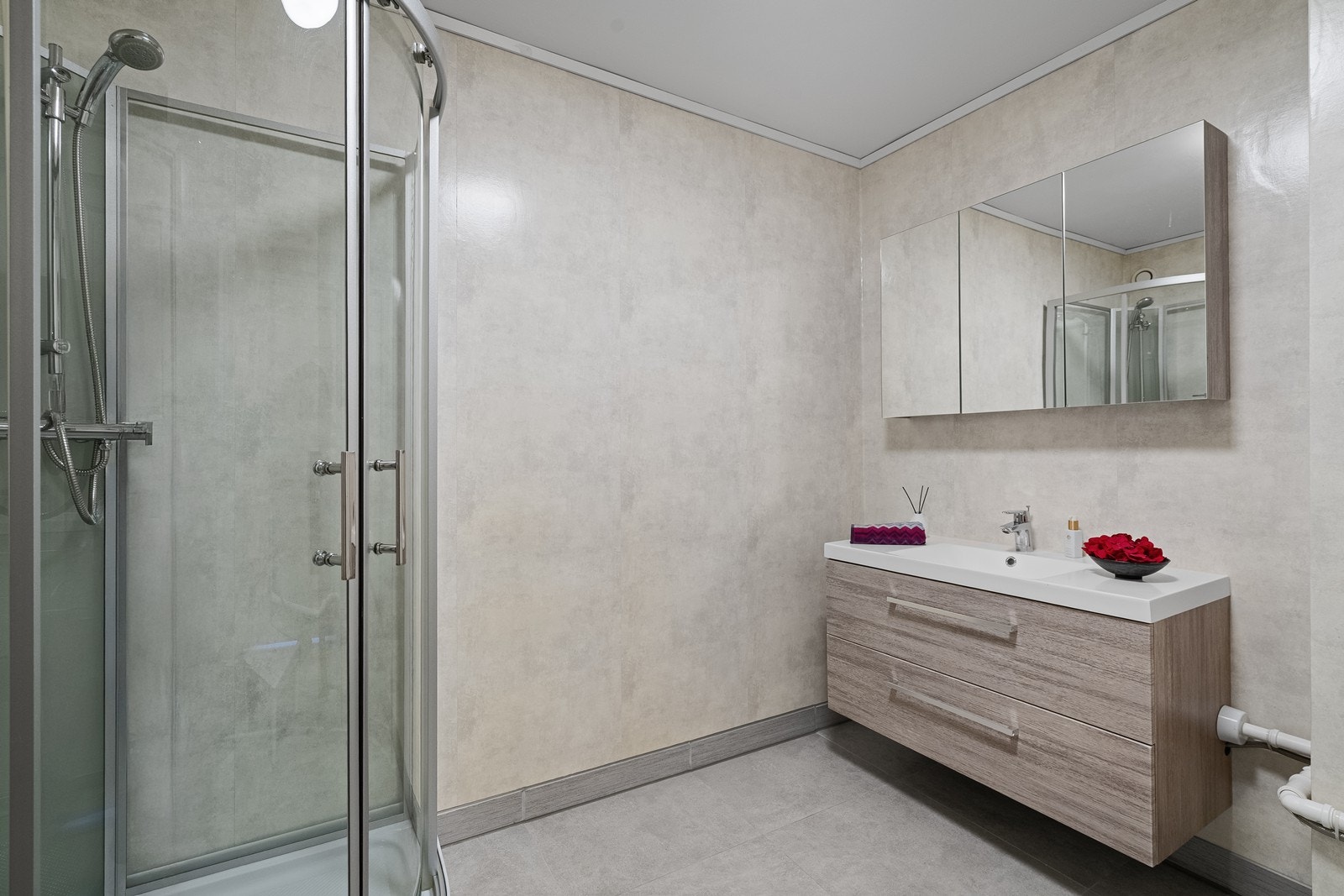 Romslig baderom i lune og tidløse farger. Hjørnedusj og innredning med tilhørende speil gir et helhetlig uttrykk. Opplegg for vaskemaskin og tørketrommel. Galleribilde