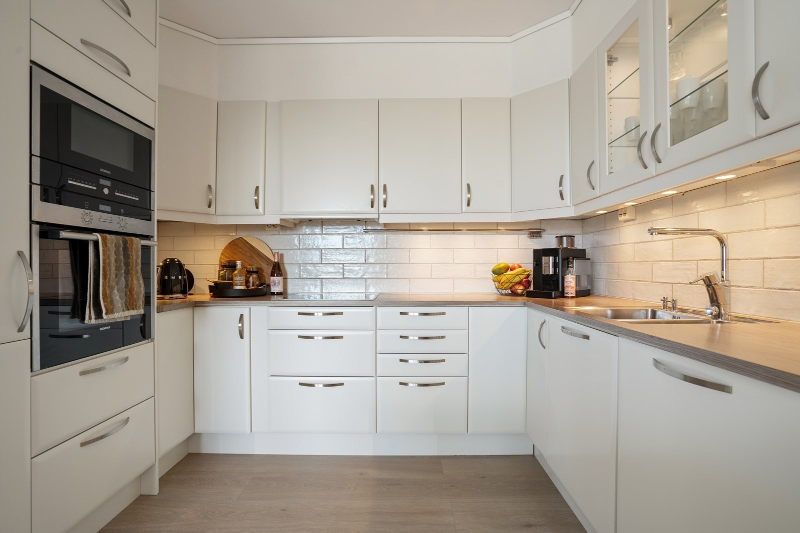 Benkeplaten er laminert og har dobbel stålvask, fliser på vegg over benk. Kjøkkenet er utstyrt med intergert komfyr, mikro, platetopp, oppvaskmaskin og kjøleskap Galleribilde