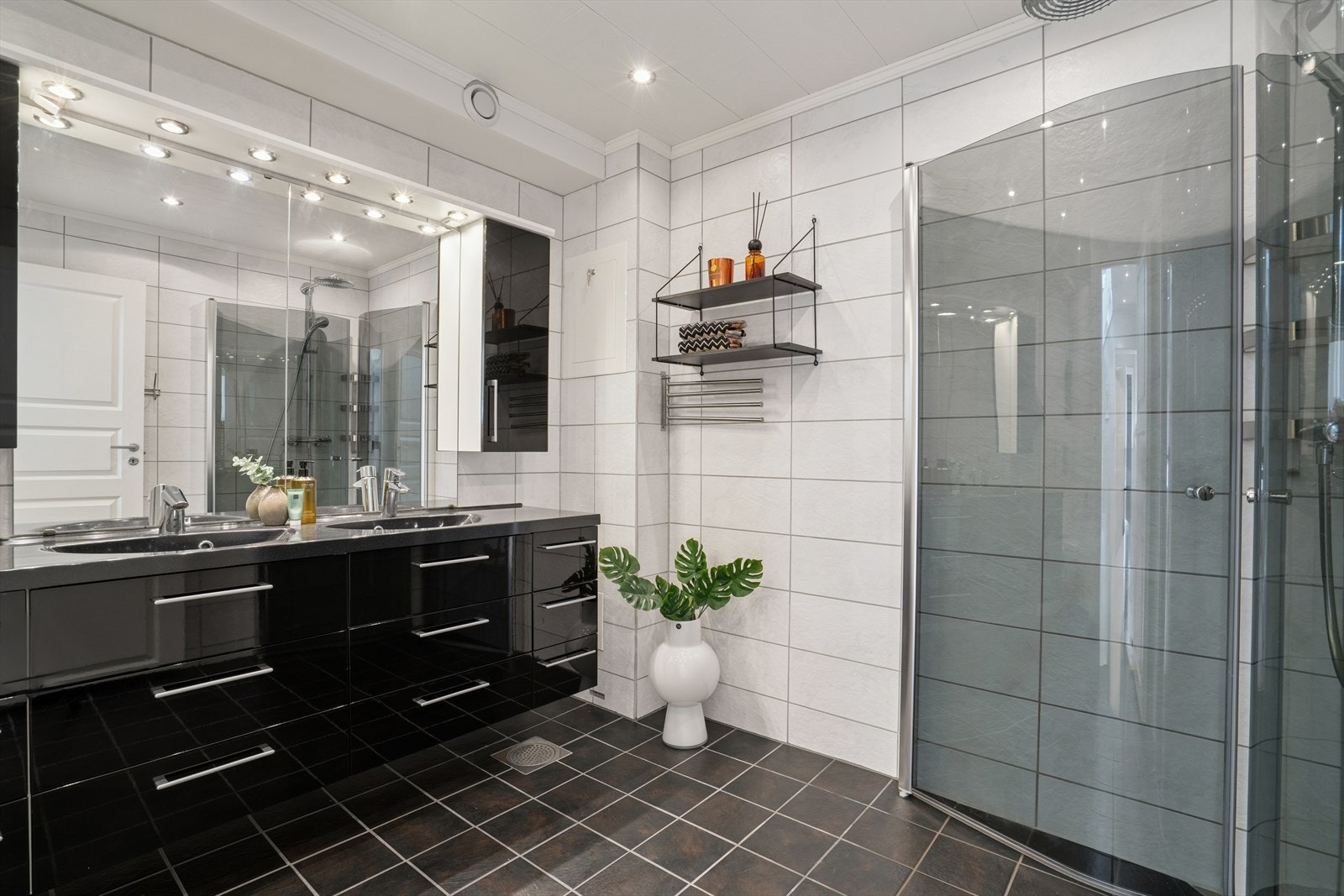 Badet er lyst med flislagte vegger og gulv som har nedstøpte elektriske varmekabler. Vegghengt toalett og dusjhjørne. Galleribilde