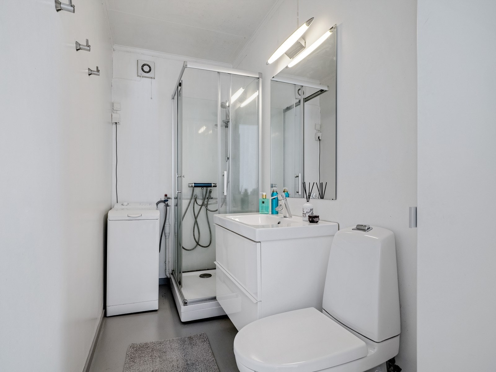 Bad i 1.etasje innredet med dusjkabinett, servant på innredning og toalett. Galleribilde