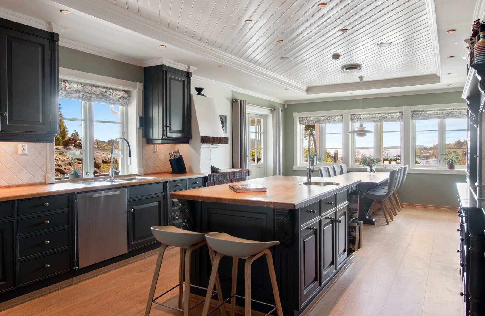 Et stort og lekkert kjøkken ligger i den ene fløyen nede, med nydelig 1-stavs heltregulv fra 2020 og veggflater malt i en trendy grønnfarge. Galleribilde