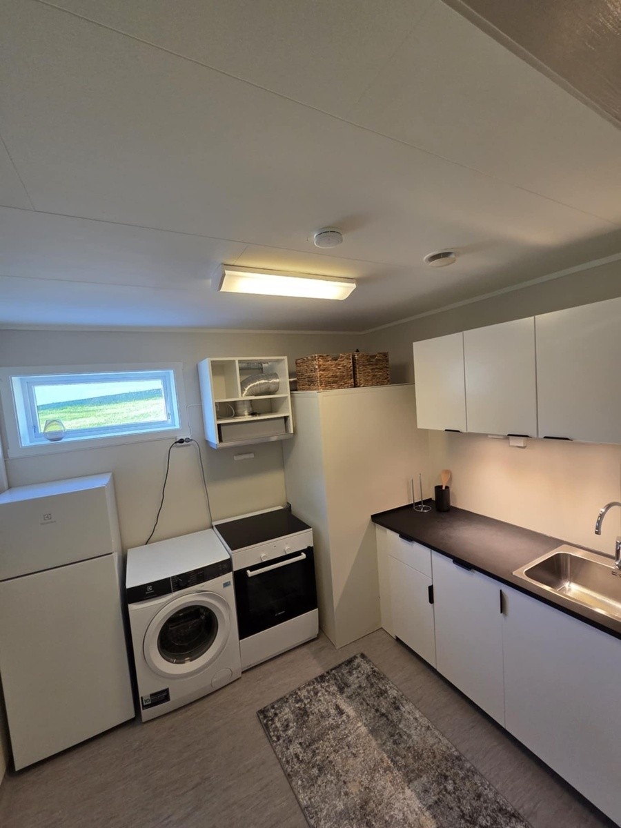 Kjøkken med komfyr, kjøleskap, oppvaskmaskinog vaskemaskin. Galleribilde