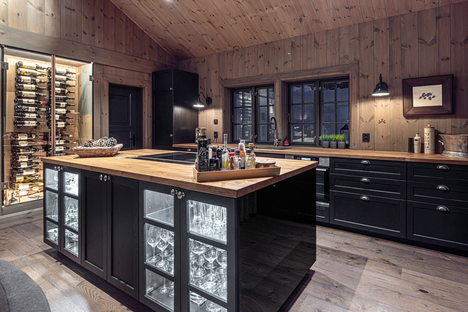 Raust kjøkken med mye skap- og benkeplass. Smart benkeplass mot spisestuen for servering. Legg merke til vinskapet som er X-faktoren på kjøkkenet Galleribilde