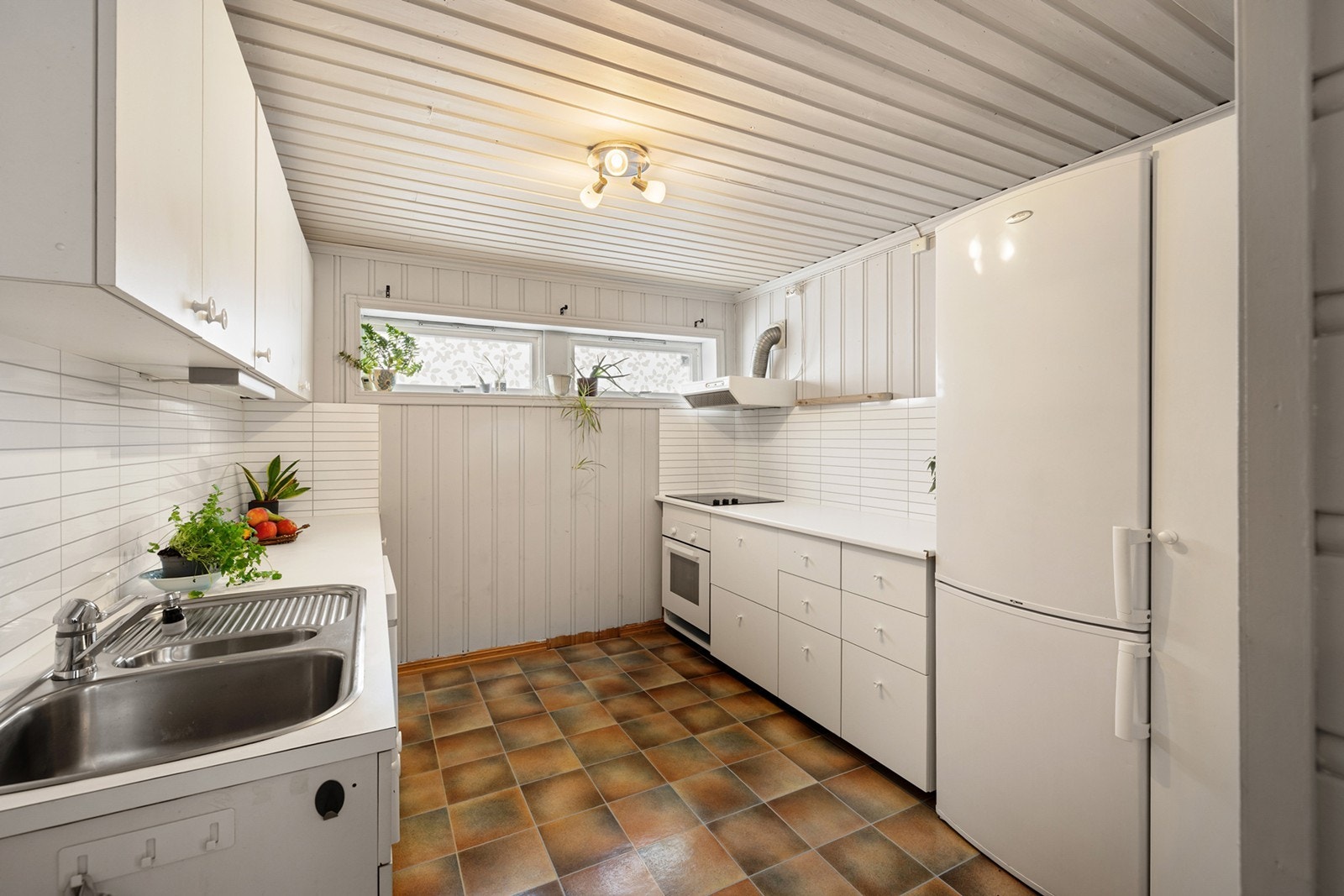 Laminert benkeplate med nedfelt oppvaskkum og integrert komfyr gir praktisk kjøkkenløsning. Galleribilde