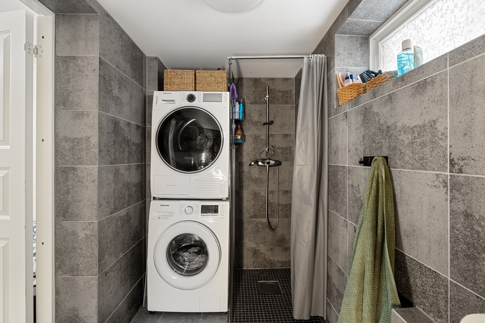 Dusjnisje med fliser og opplegg for vaskemaskin gir praktisk funksjonalitet. Galleribilde