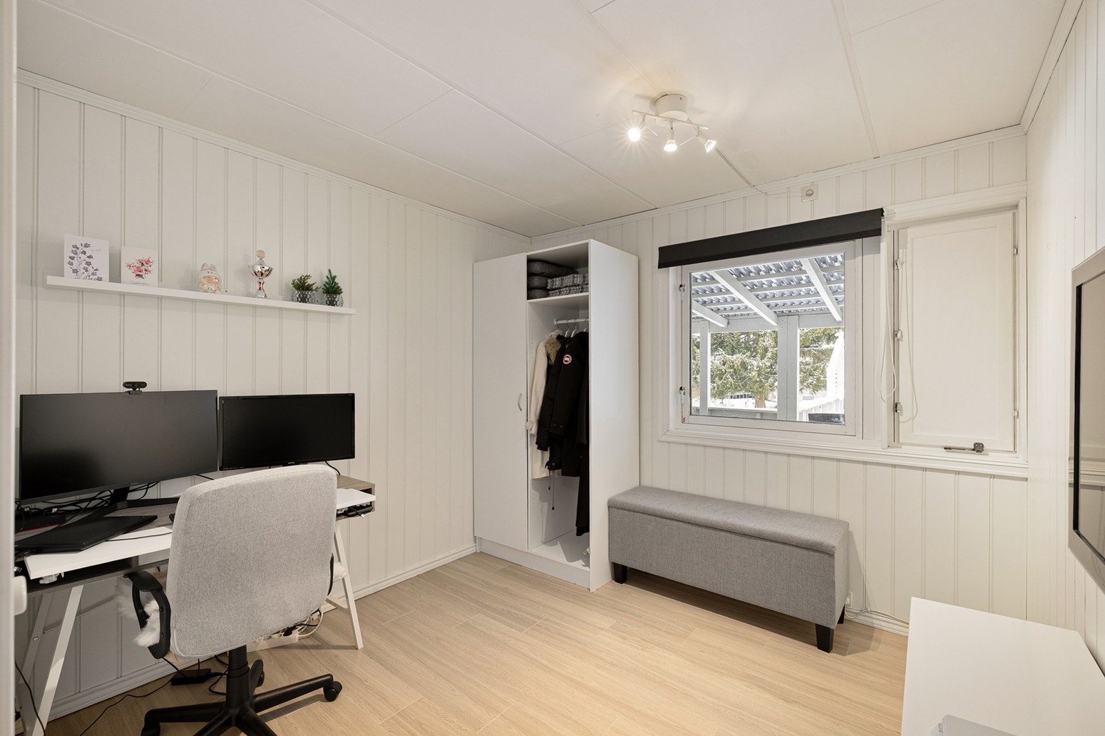 Laminatgulv og malte panelvegger gir et lyst arbeidsrom med praktisk garderobeløsning. Galleribilde