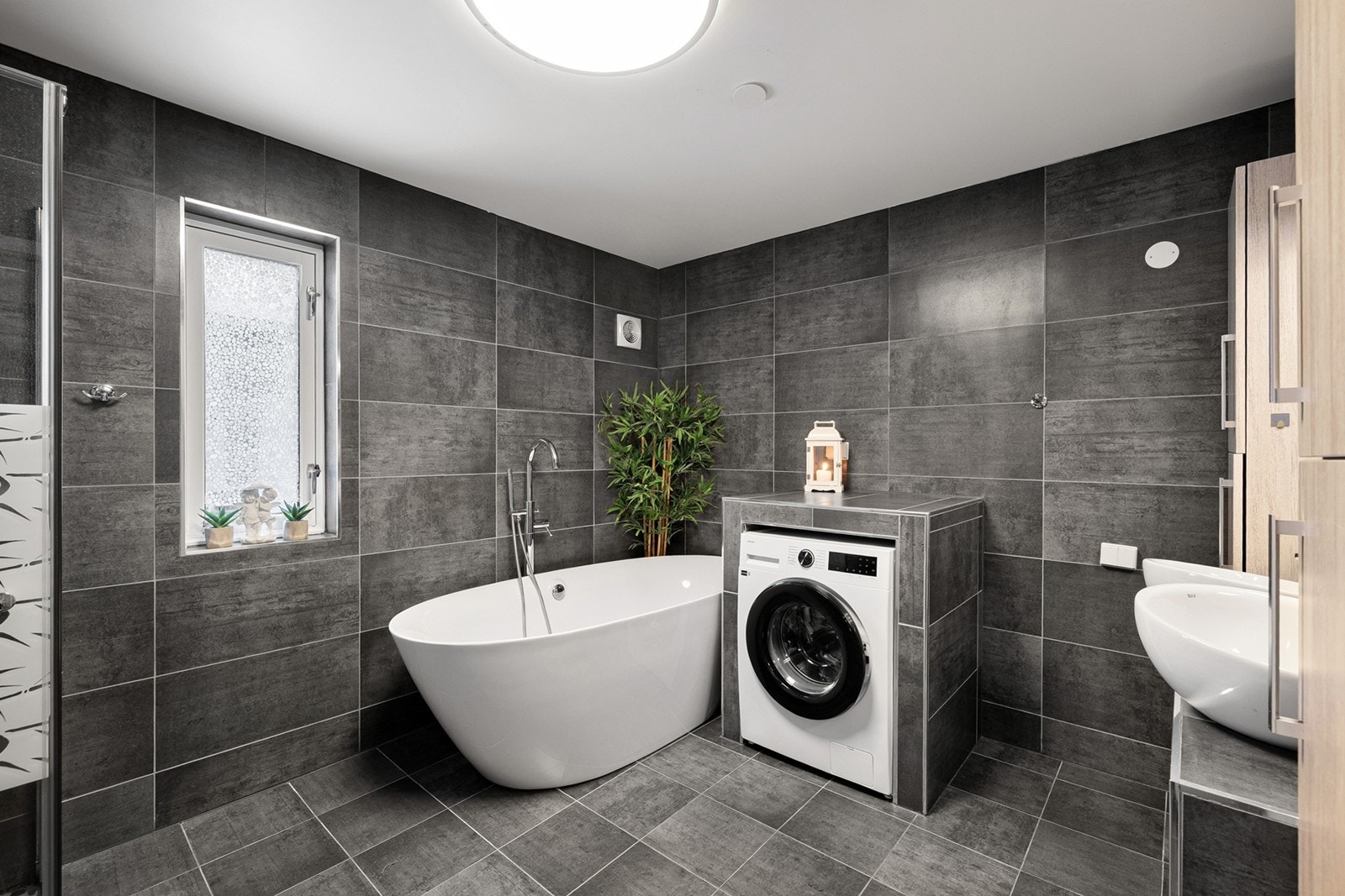 Moderne bad med badekar og pen løsning til vaskemaskin. Galleribilde