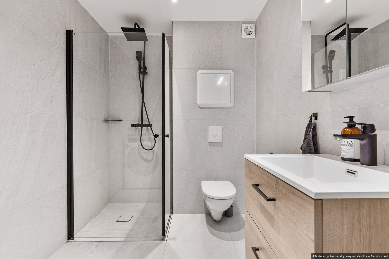 Badet har nydelige fliser og lekker dusj, vegghengt toalett, servantinnredning samt opplegg for vaskemaskin. Varmekabler i gulv. Galleribilde