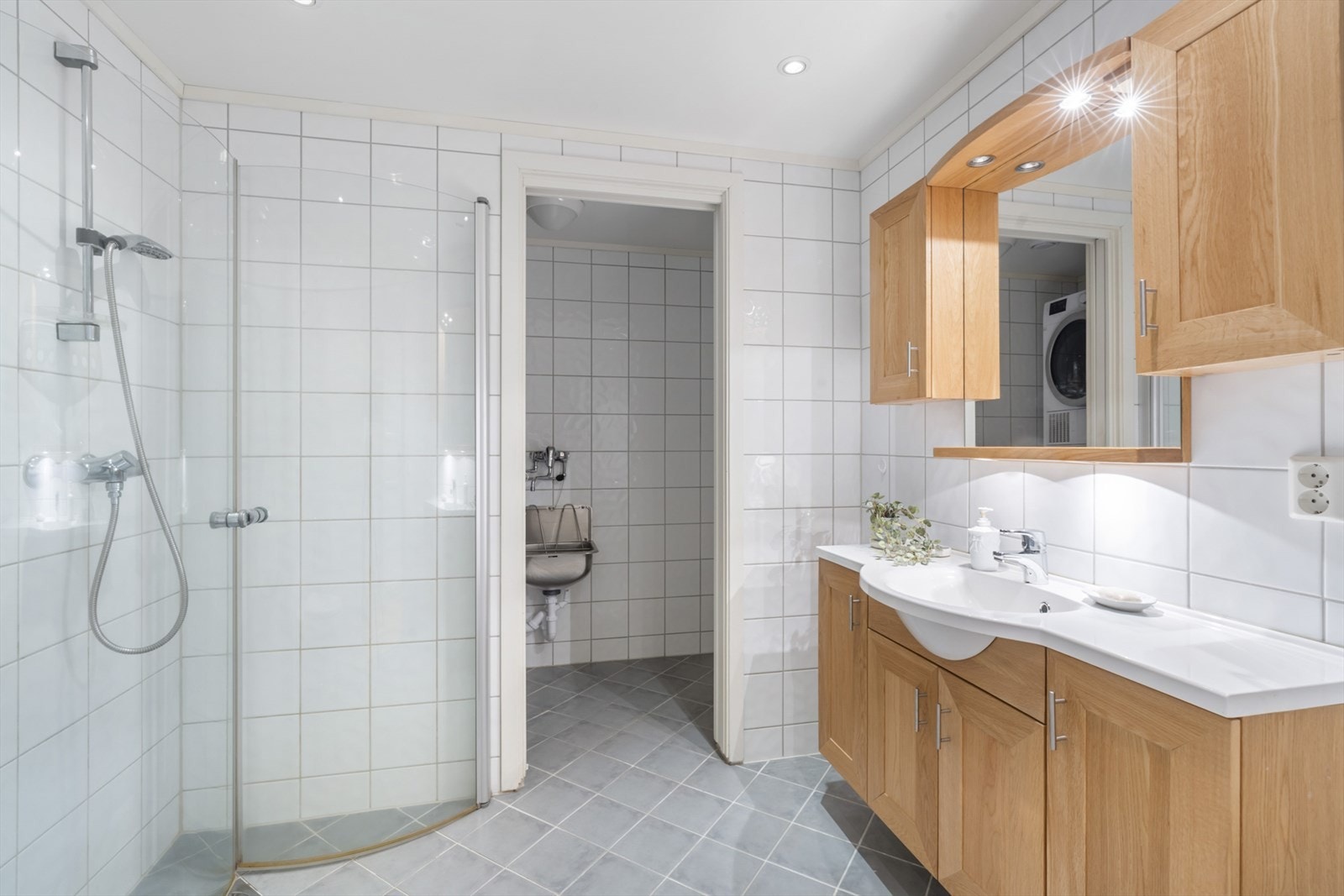 Flislagt bad med vegghengt toalett og dusjnisje. Vaskerom innenfor adskilt med skyvedør. Galleribilde