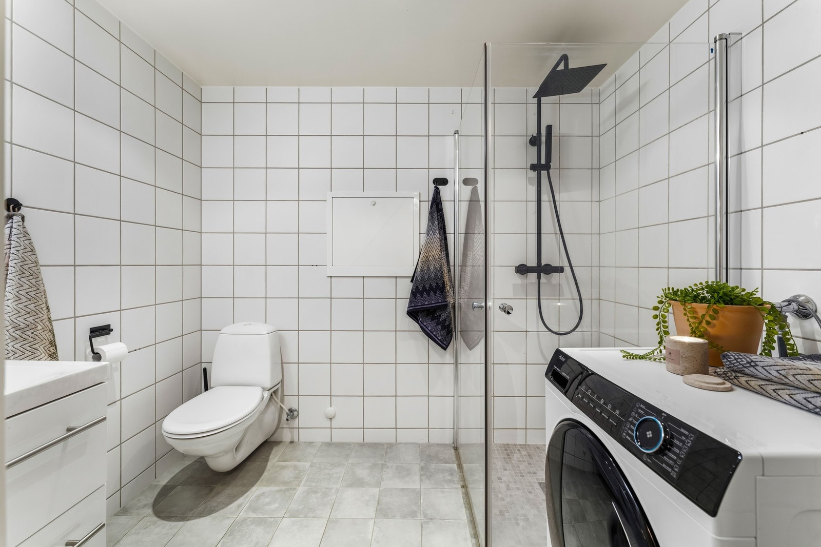 Lyst og pent flislagt bad med varmekabler i gulv, downlights i himling og opplegg for vaskemaskin. Innredningen består av dusjnisje som er utstyrt med både regnfallsdusj og hånddusj, samt veggmontert toalett. Galleribilde