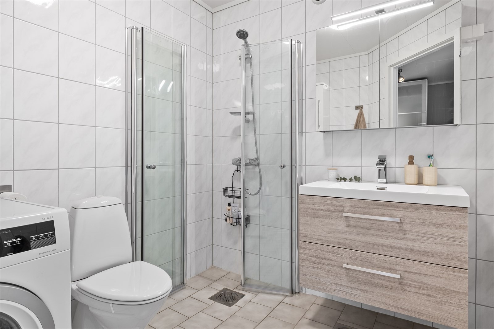 Badet er fra byggeår og er flislagt på gulv og vegger, med malte flater i tak Galleribilde