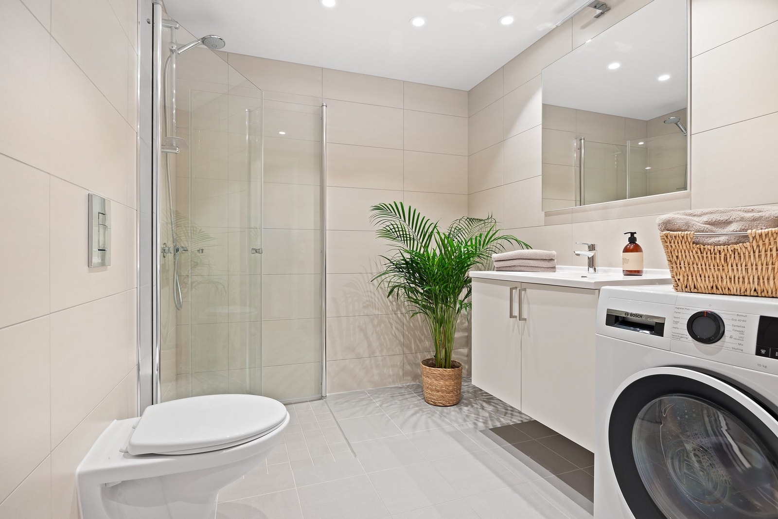 Pent flislagt bad med varmekabler i gulvet og opplegg for vaskemaskin/tørketrommel Galleribilde