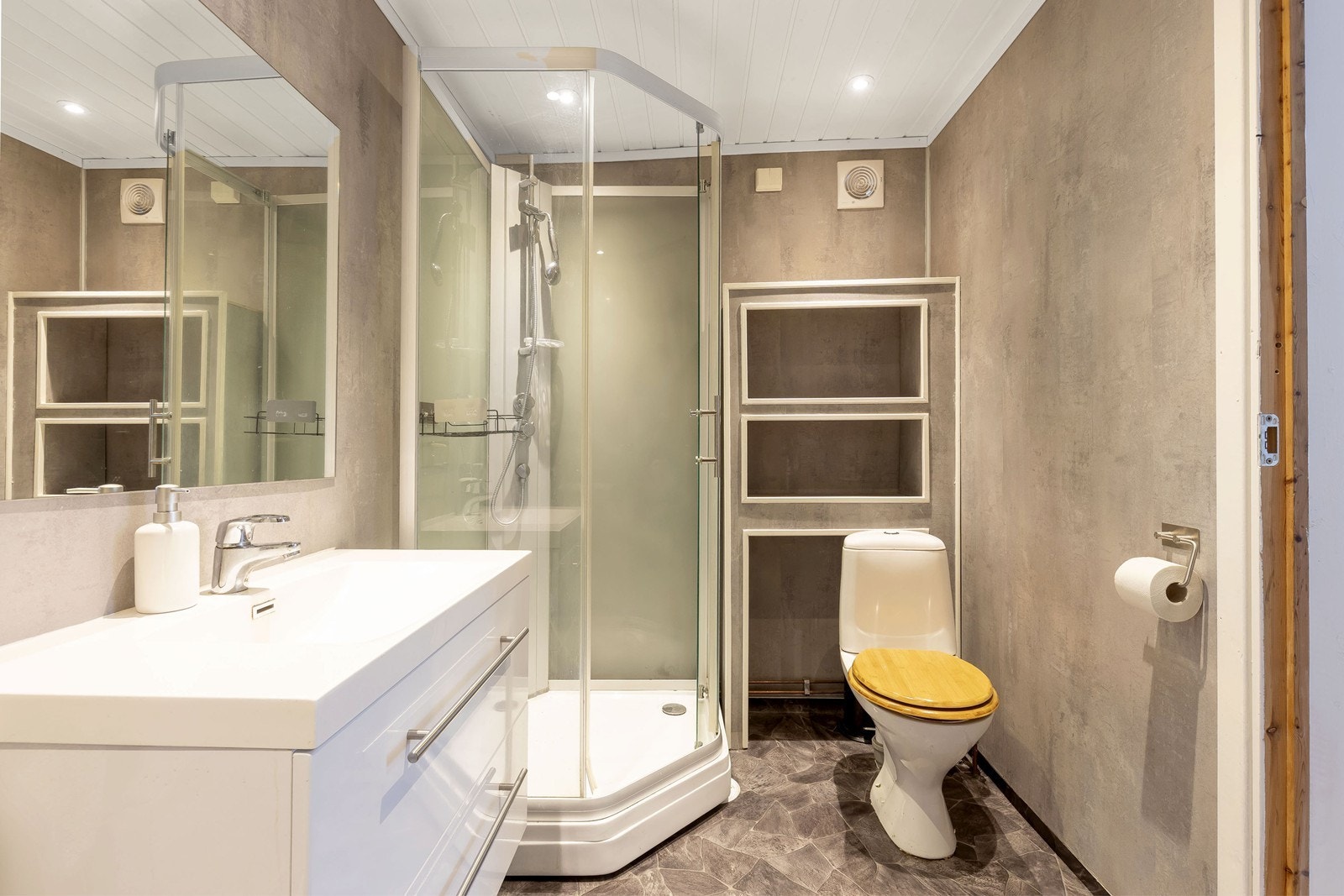 Badet på ca 10 kvm gir deg alt du trenger, og har innebyggd oppbevaringsmuligheter i samme stil som badeet Galleribilde