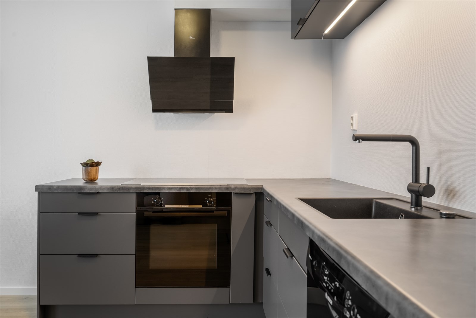 Moderne kjøkken med stilrene fronter, integrerte hvitevarer og praktisk arbeidsflate. Galleribilde