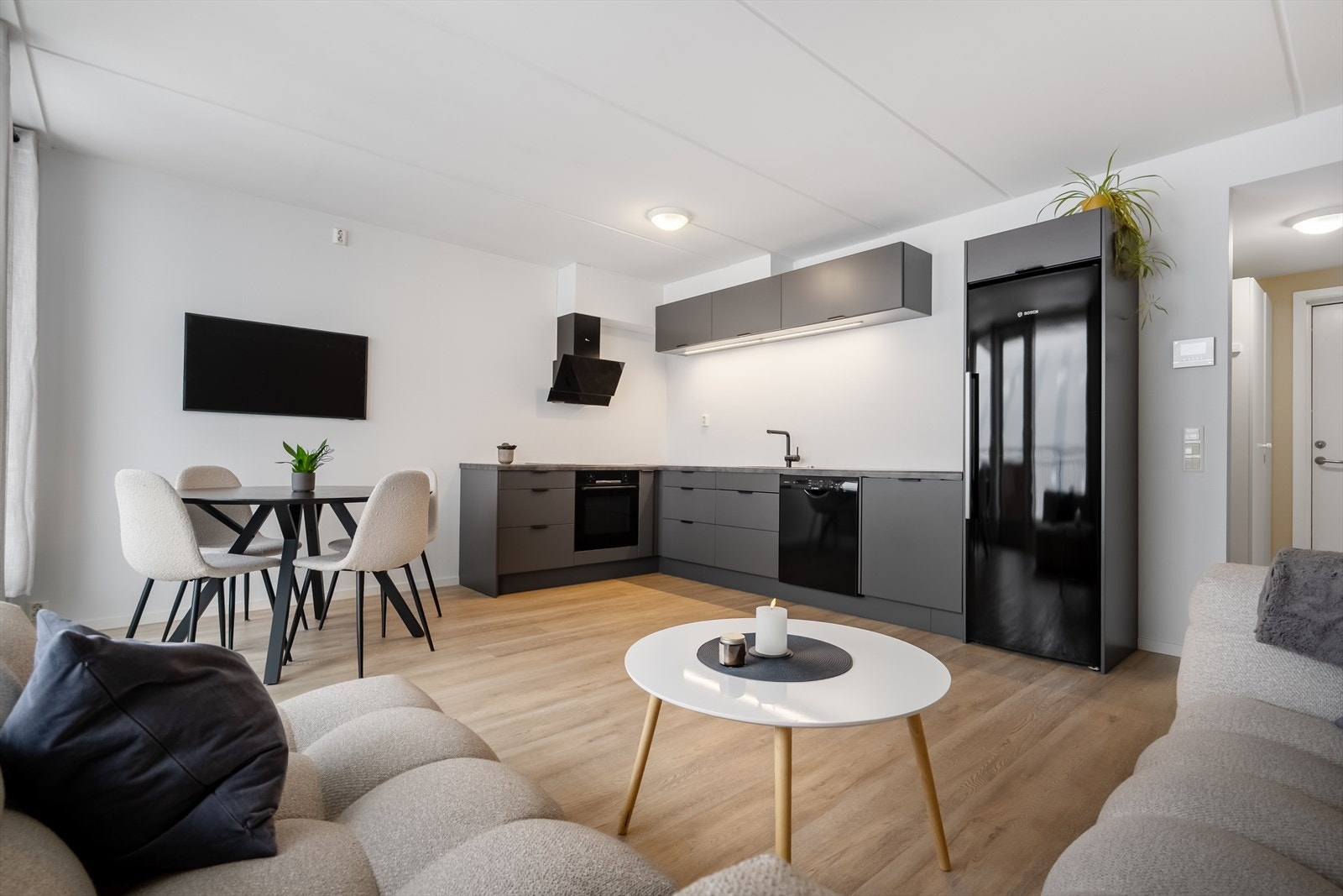 Moderne og lys stue med åpen kjøkkenløsning, stilrene grå kjøkkenfronter. Galleribilde