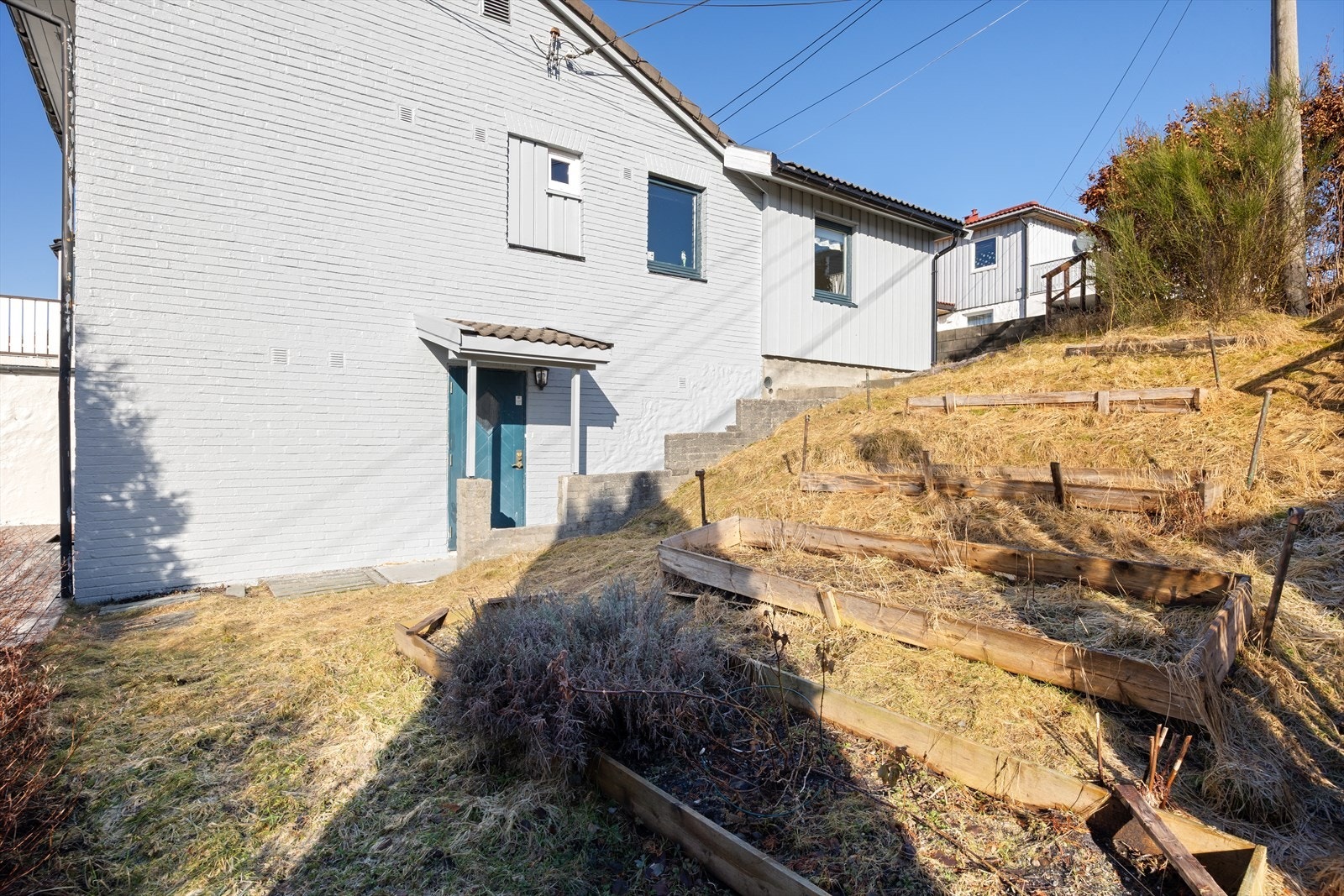 Nymalt fasade i 2025 - Inngangsparti til underetasjen og utleiedel Galleribilde