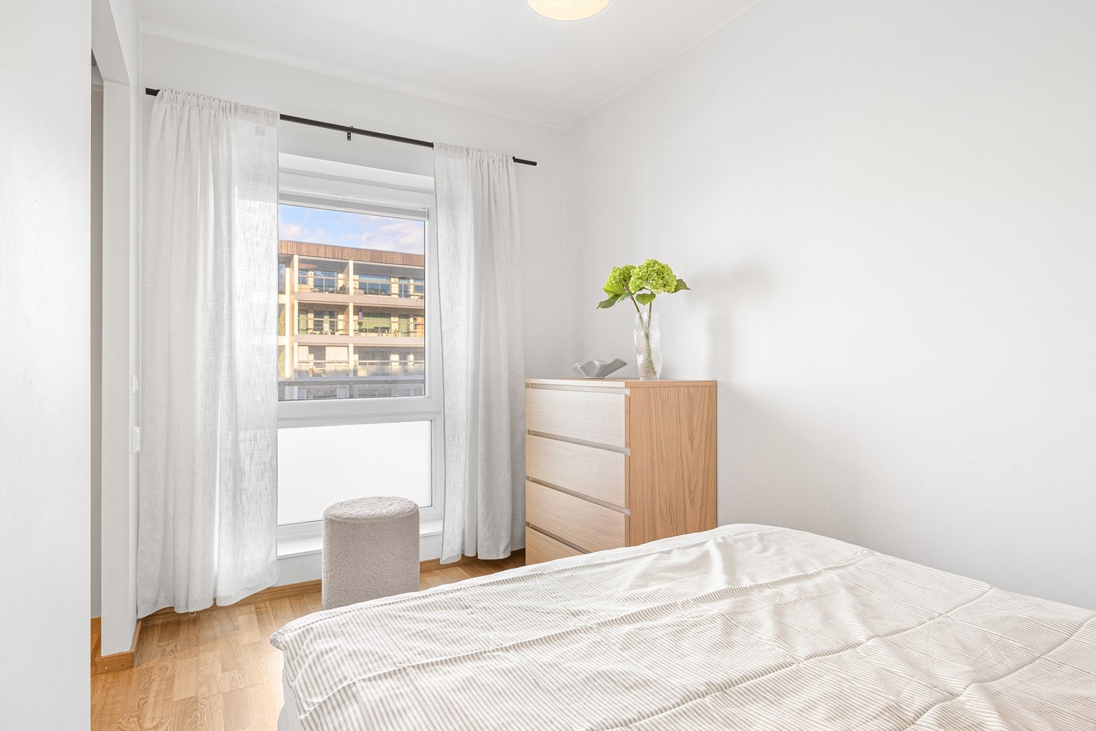 De store vindusflatene på soverommet er vendt mot sameiets rolige fellesarealer, og slipper inn rikelig med naturlig dagslys på morgen og formiddag. Galleribilde