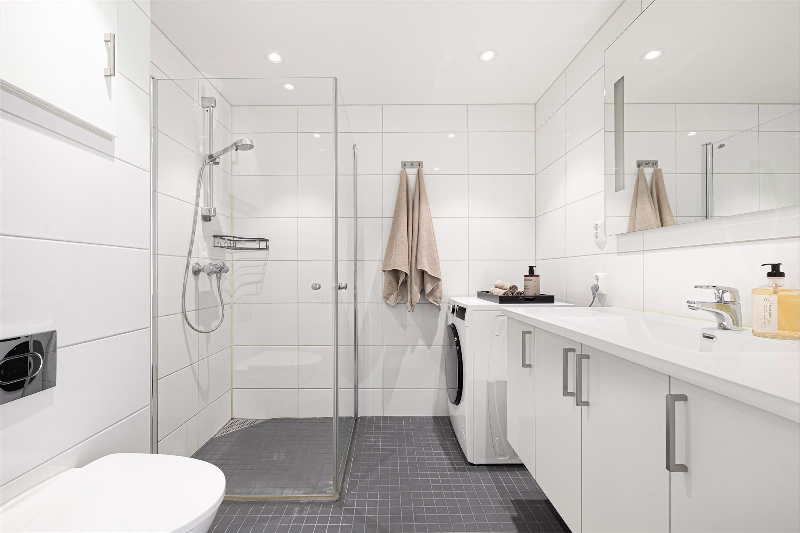 Det 4,5 m² store badet fremstår som innbydende med helflisede overflater, behagelig gulvvarme og downlights i tak. Galleribilde