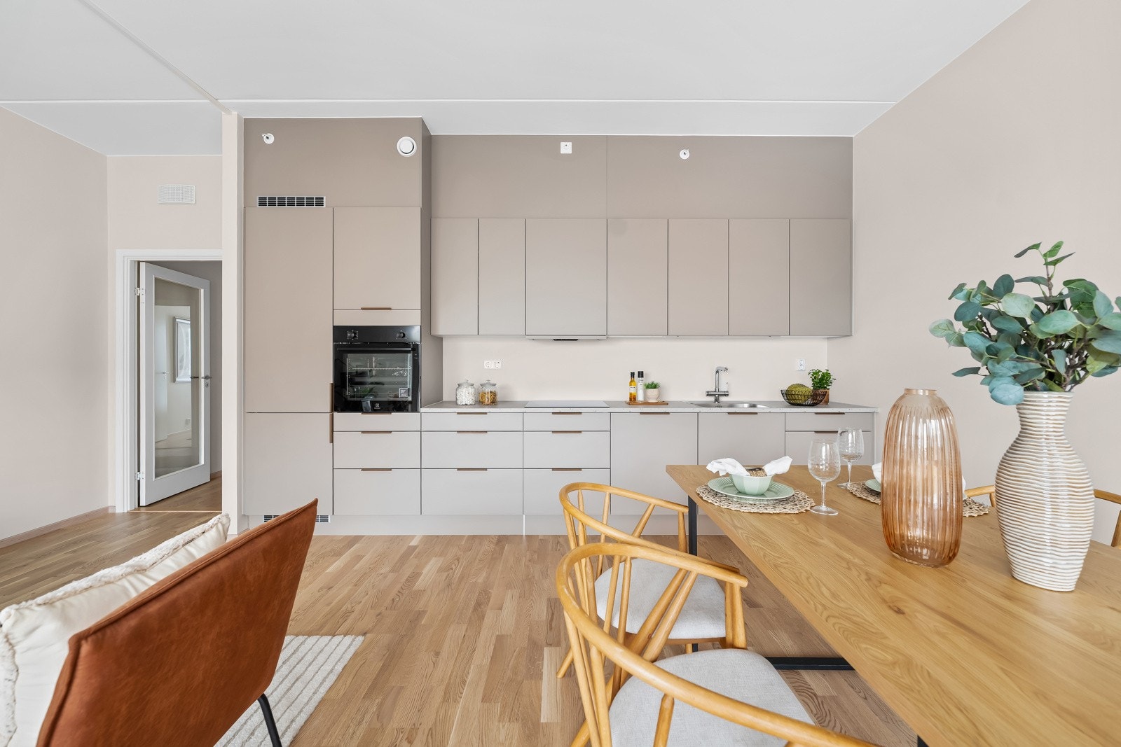 Stilrent HTH-kjøkken med beige, slette fronter og laminat benkeplate med nedfelt vaskekum. Integrerte hvitevarer medfølger. Galleribilde