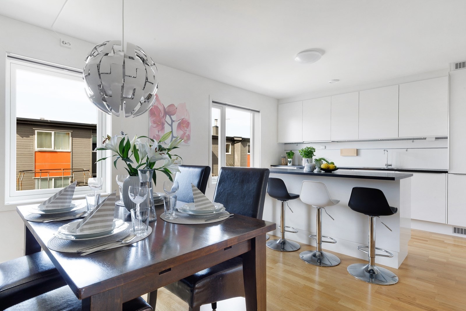 Tidløst og moderne kjøkkeninnredning med hvite, slette fronter og mørk benkeplate. Galleribilde