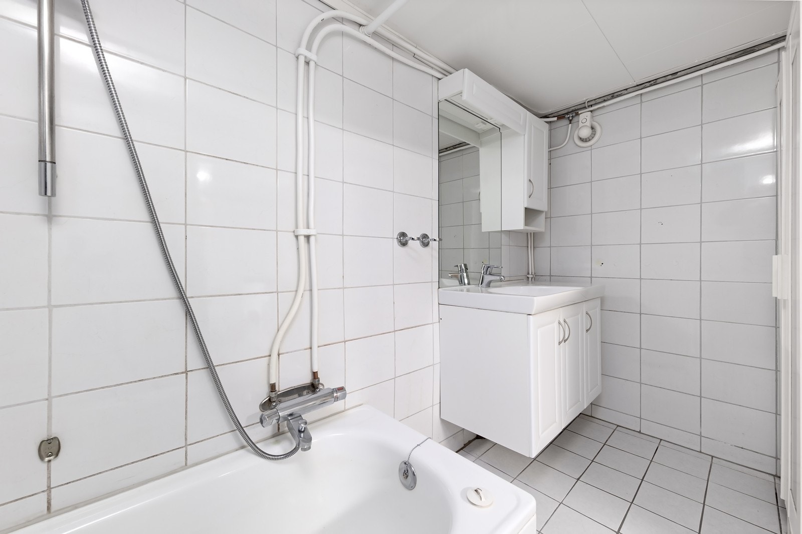 Flislagt bad i underetasjen med badekar og baderomsinnredning med servant. Galleribilde